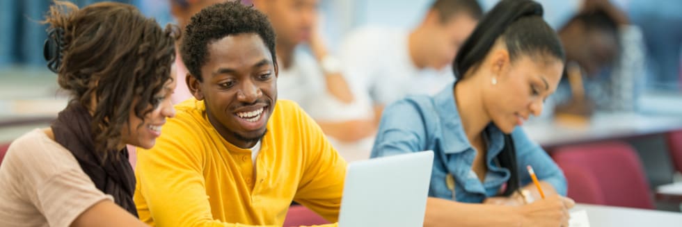 Students engaging in discussion near a laptop.