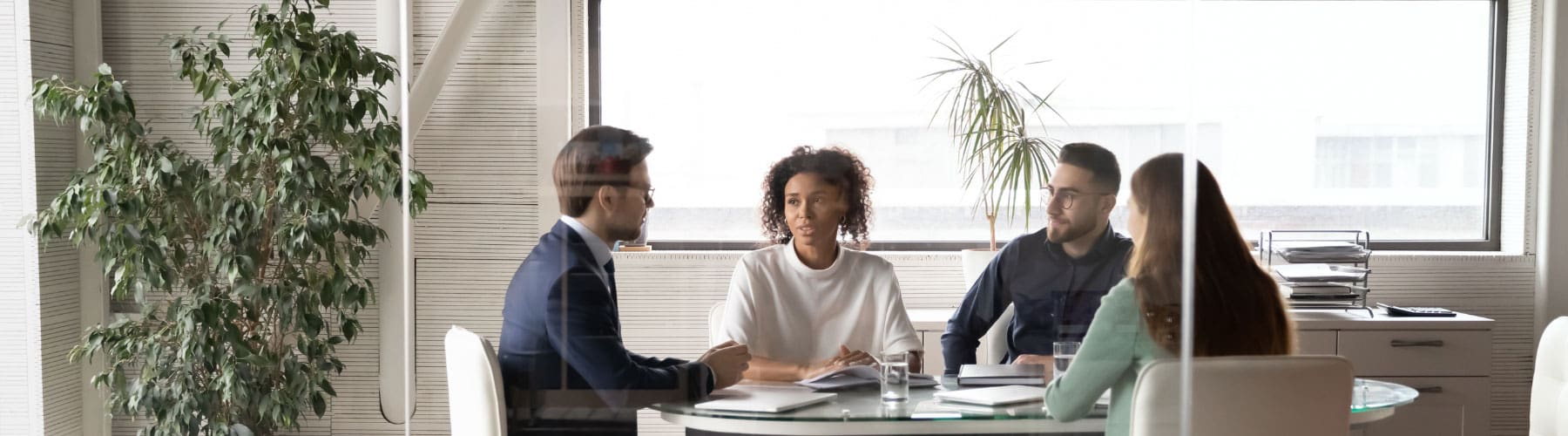 A group of lawyers sits at a table with laptops.