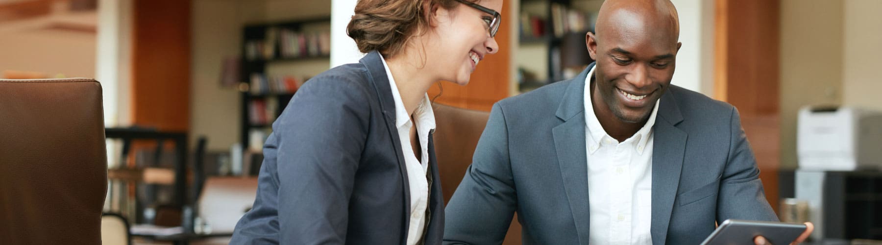 Coworkers look at a tablet and talk about business strategies in the office.