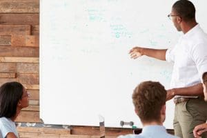 A team leader addresses a working group seated around a conference table.